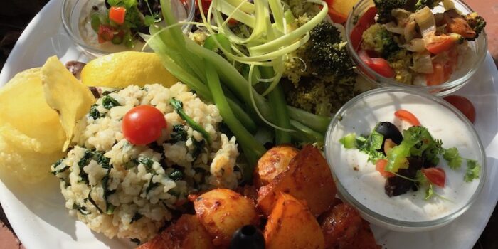 A tapas plate with rice, potatoes, fried veggies and a selection of raw goodness, with a portion of our famous Aioli.