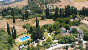 Birds-eye view of Finca Vegana with the pool, parking lot, holiday homes, riverbed and grassland