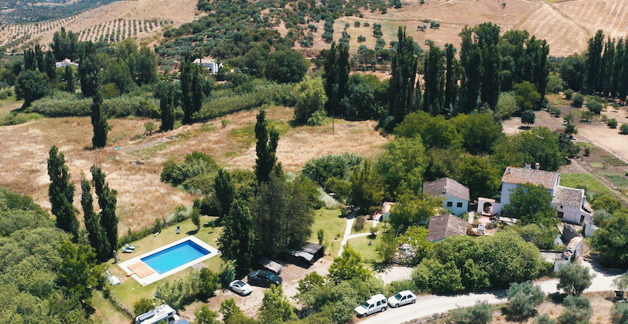 Finca Vegana aus der Vogelperspektive mit großem Pool, Parkplatz, den Ferienhäusern und dem grünen Tal